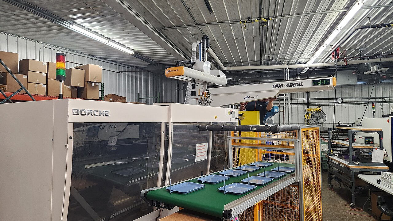 Injection molding machine with a robotic take-out arm in a production cell