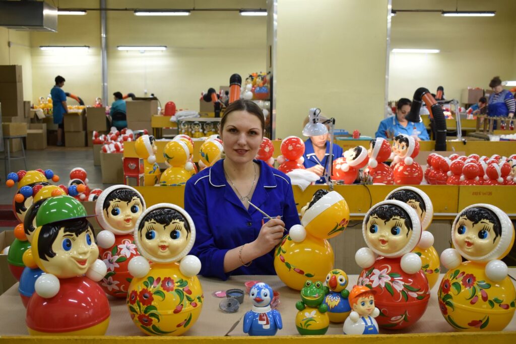 Workers hand-painting finished toy figures on a toy manufacturer's production line